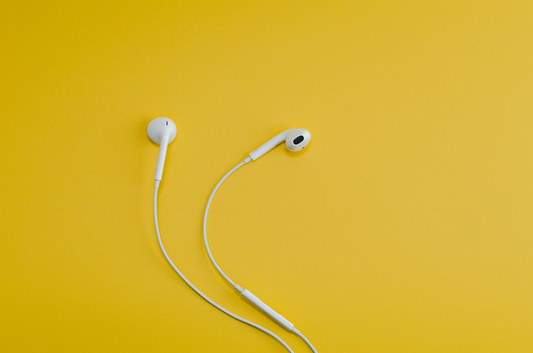 White wired earbuds on a yellow background, illustrating M4A to MP3 audio conversion
